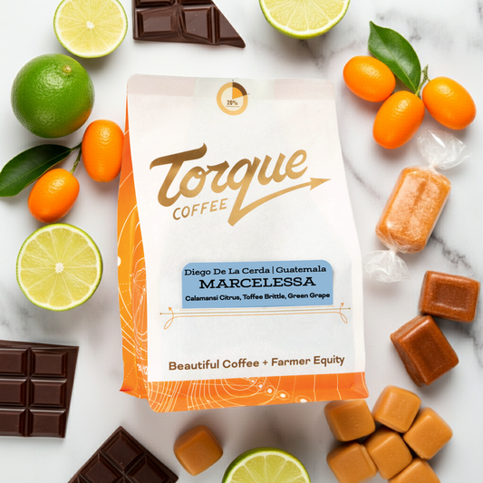 Torque Coffee package surrounded by limes, oranges, and chocolate on a marble surface