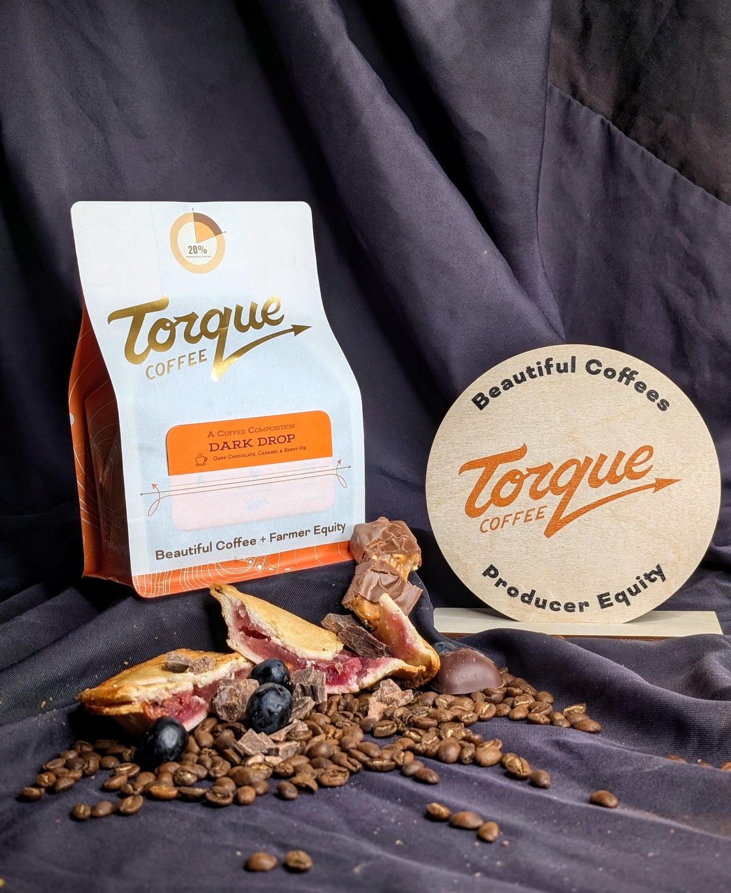 Torque Coffee package with coffee beans and a pie on a dark fabric background
