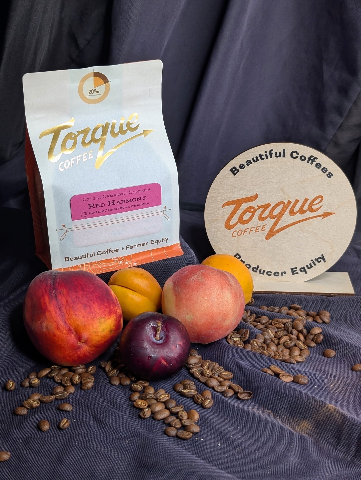 Torque Coffee package with coffee beans, peaches, and a coaster on a dark background